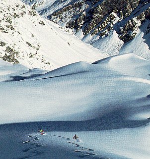 Skiers cut deep powder.