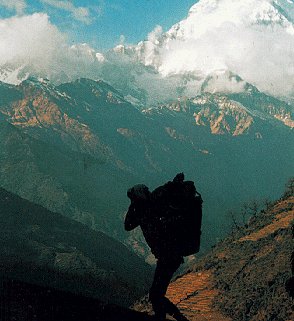 Porters carrying gear beneath snowcapped peaks.